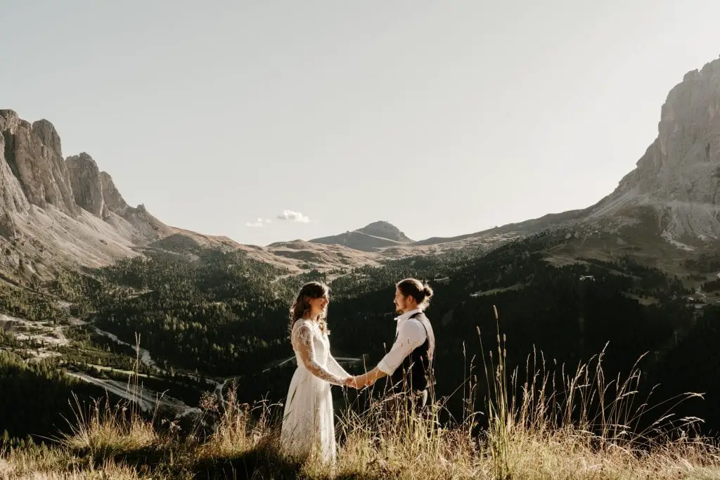 Couple standing in a field holding hands.