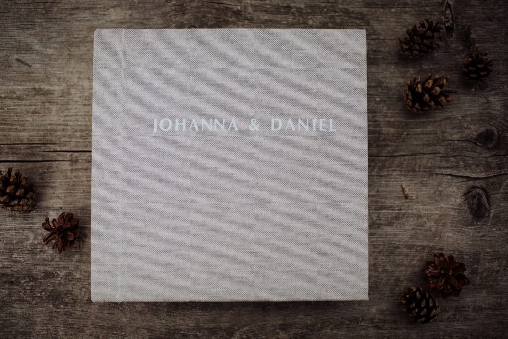 Wedding photo album with a linen cover lying on a wooden table. A great way to diversify your photography business income