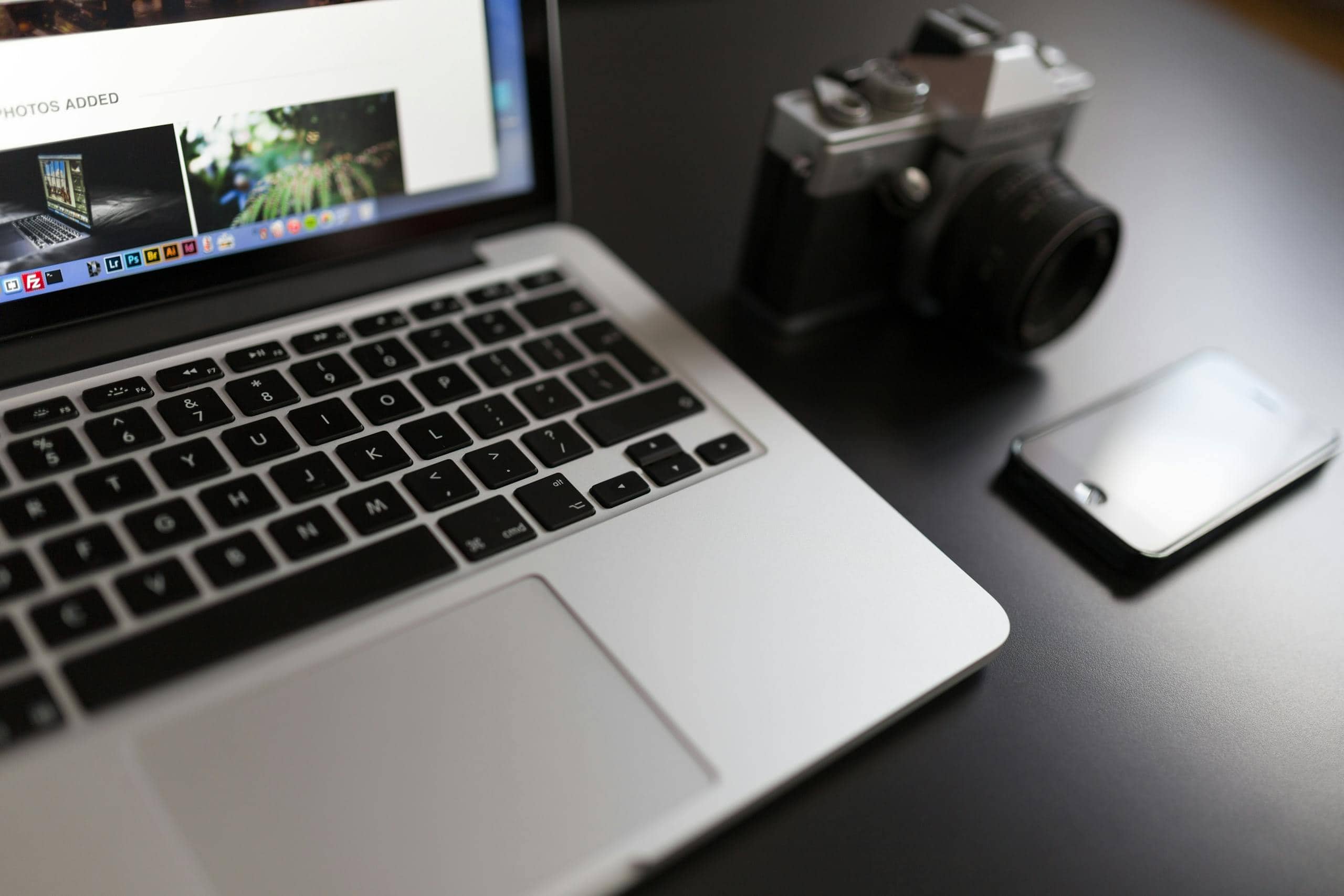 Silver Laptop Computer Beside of White and Black Camera and Black Iphone