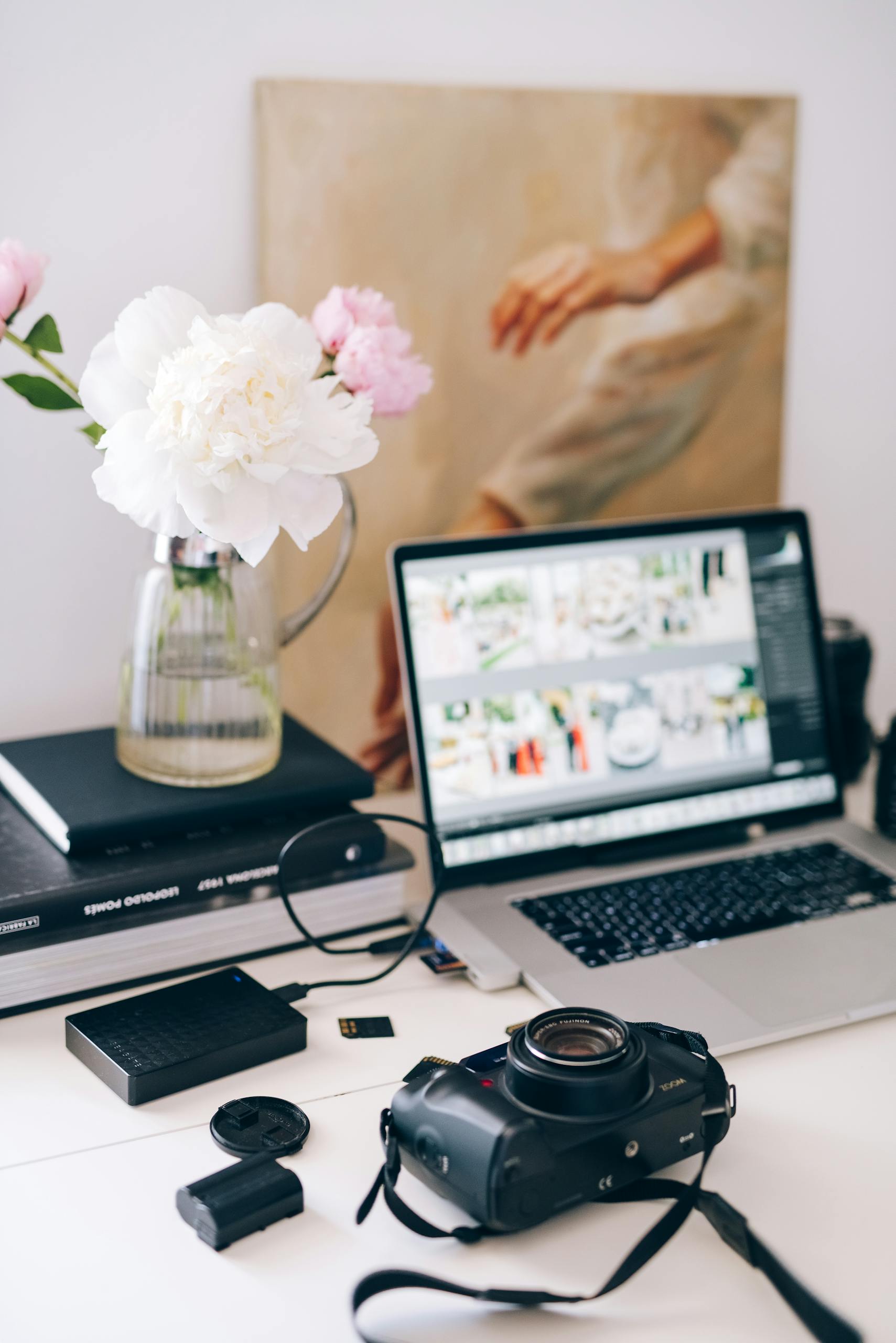 A beautifully arranged workspace with a camera, laptop, and flowers